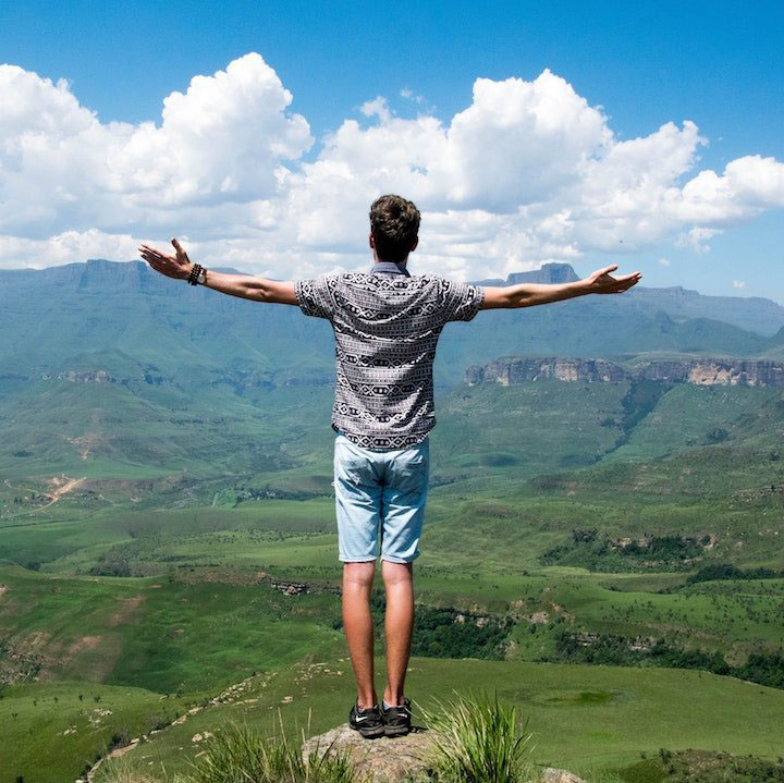 Man on a cliff raising his arms in appreciation at the view